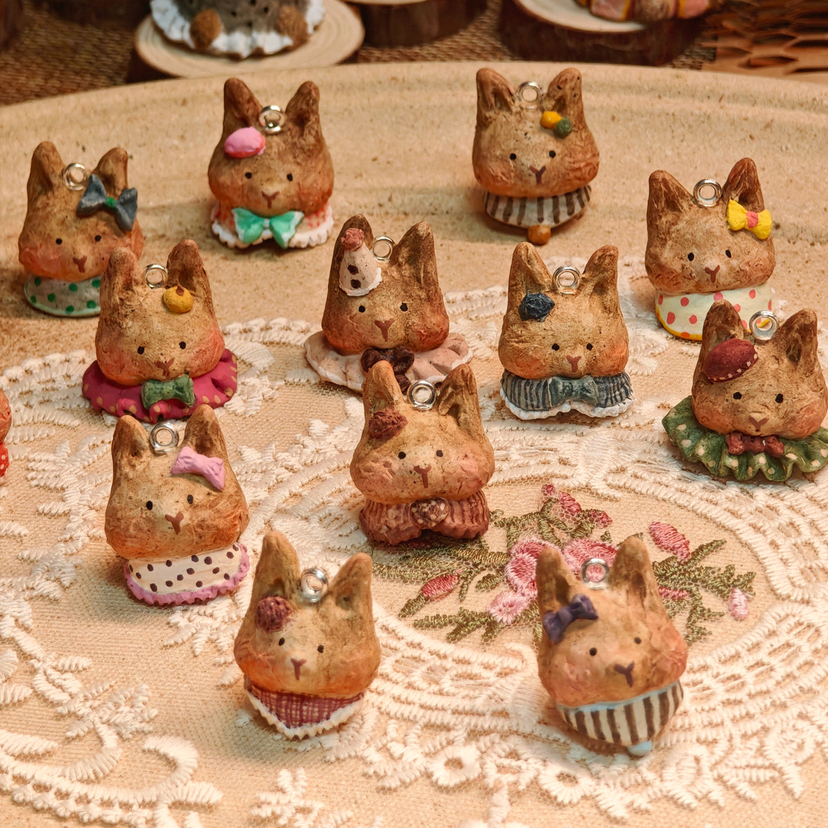 Winterwood rabbit pendants with colorful bows and collars arranged on cream lace.
