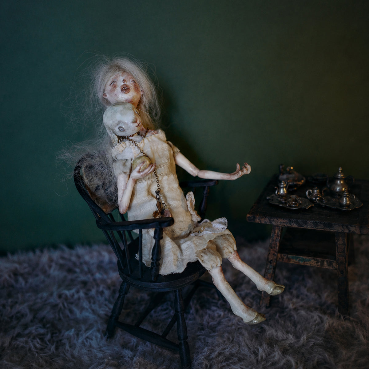 Lambwick art doll with a small lamb companion seated on a black chair against a green background.