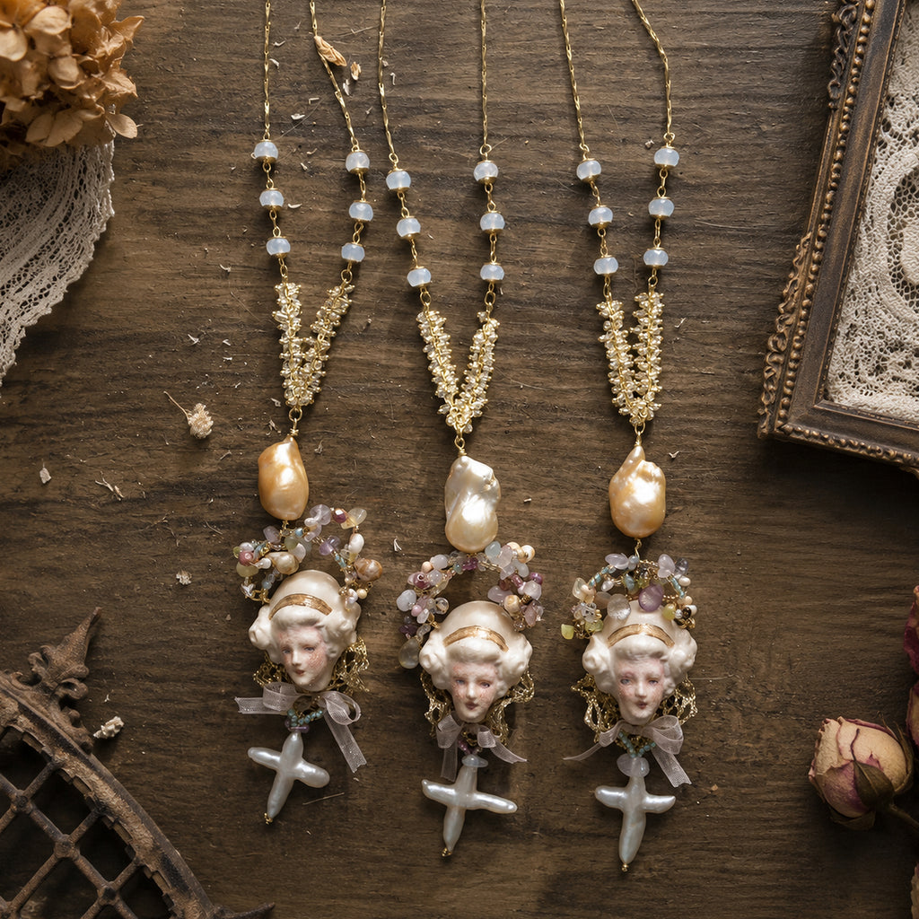 Three Odette Cross doll necklaces with different bead and face arrangements displayed side by side.