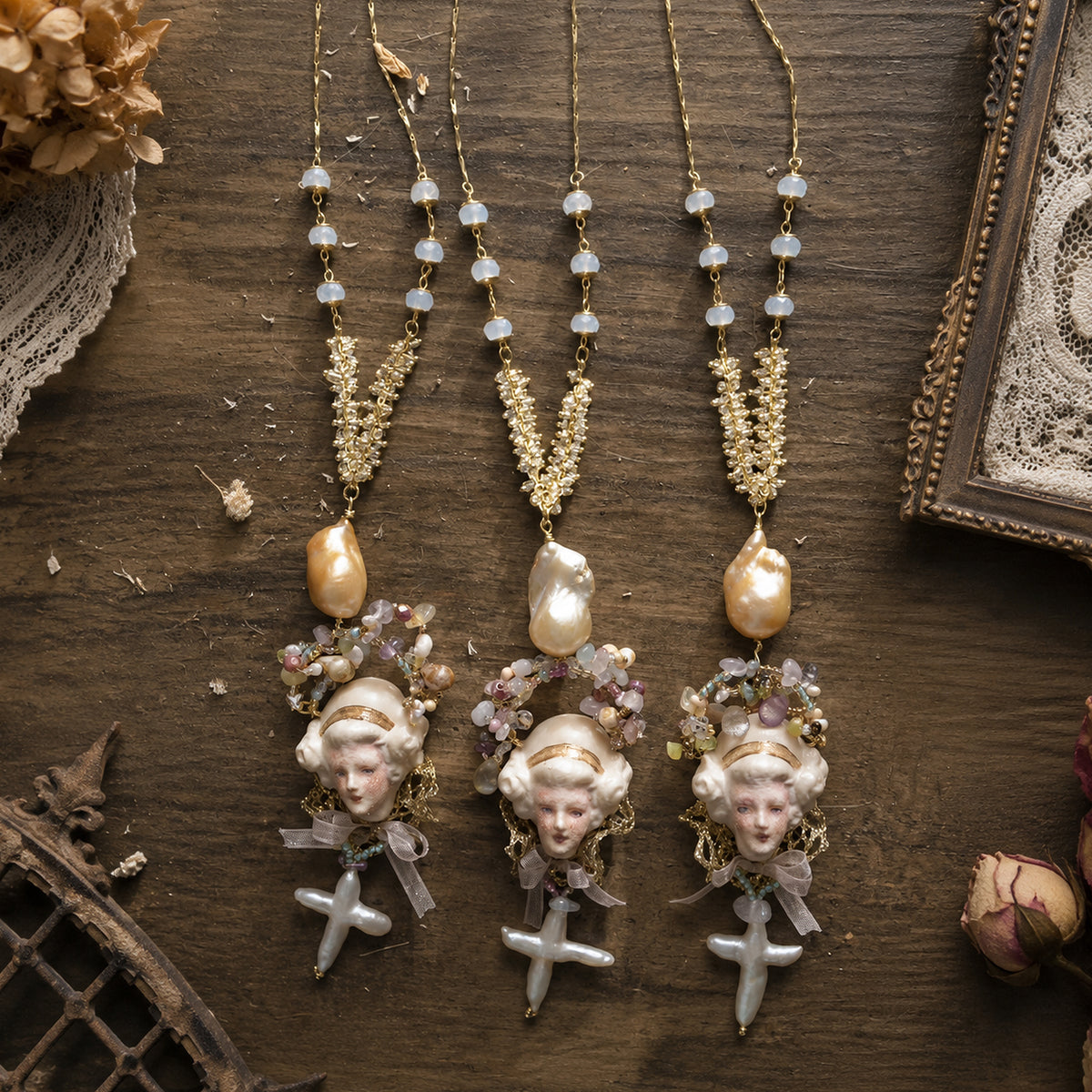 Three Odette Cross doll necklaces with different bead and face arrangements displayed side by side.