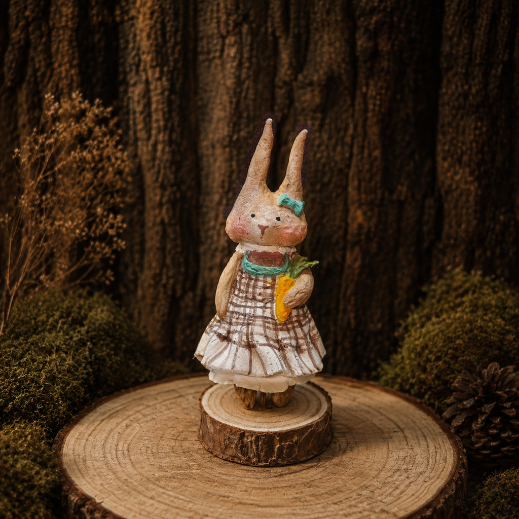 Front view of a Willowwick rabbit doll in a checked dress with a green scarf and carrot.