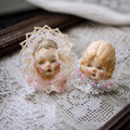 Lambwick Giant Baby and Pumpkin Head doll rings with pale lace and colorful bead collars.