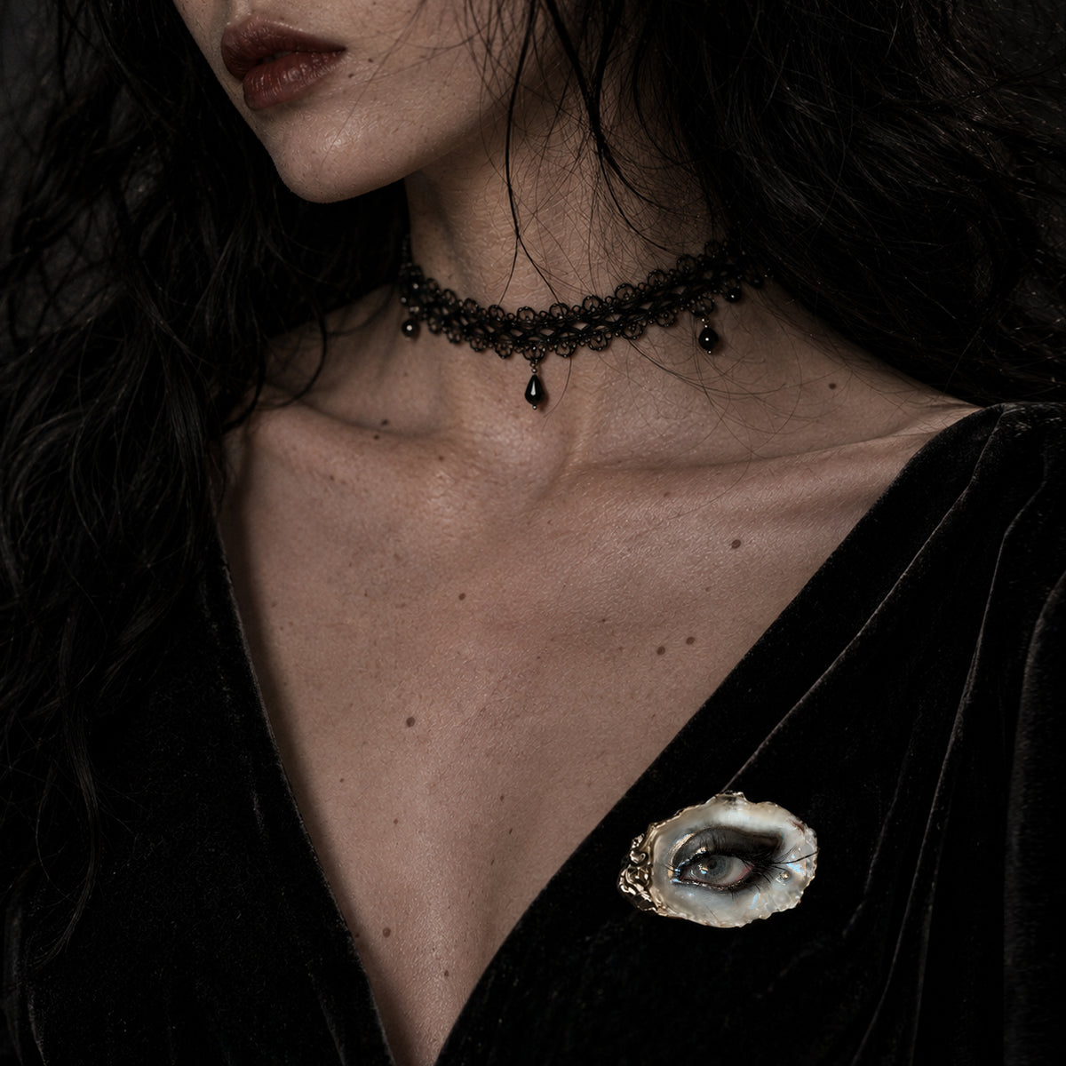 Lilith Veil Black Smoky shell-eye brooch worn on a black V-neck top.