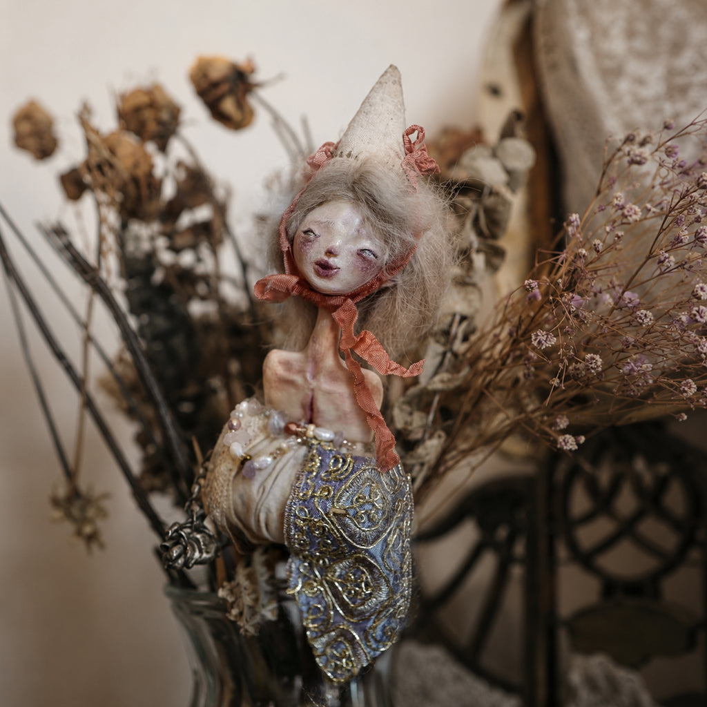 Lambwick doll hand-bell sculpture with pale hair, a cream cone hat and ornate blue-and-gold details.