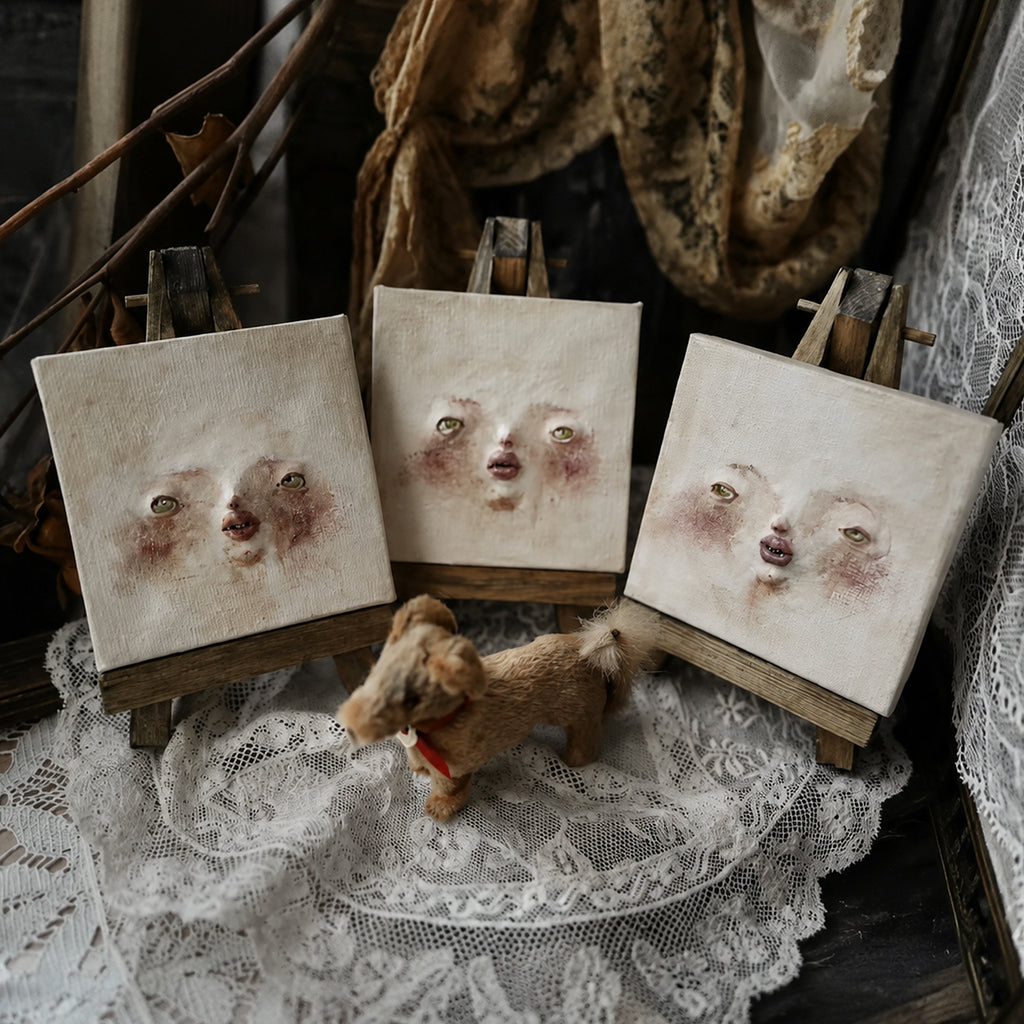Three square Lambwick clay-relief portraits arranged together with lace and dried flowers.