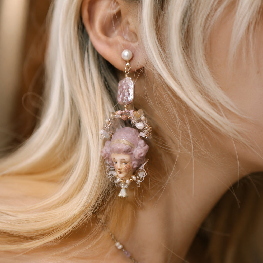 Odette doll-face earring worn on an ear, showing the long beaded arrangement.