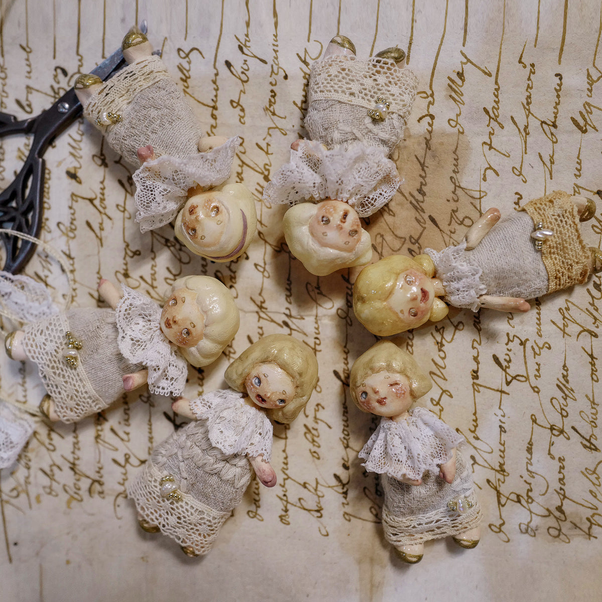 Six miniature Lambwick resident doll designs with lace collars and fabric clothing.