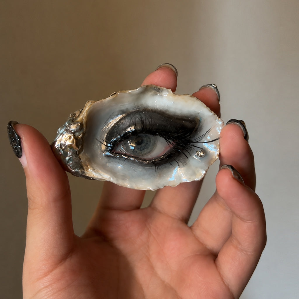 Lilith Veil Black Smoky oyster eye held in a hand to show its scale.