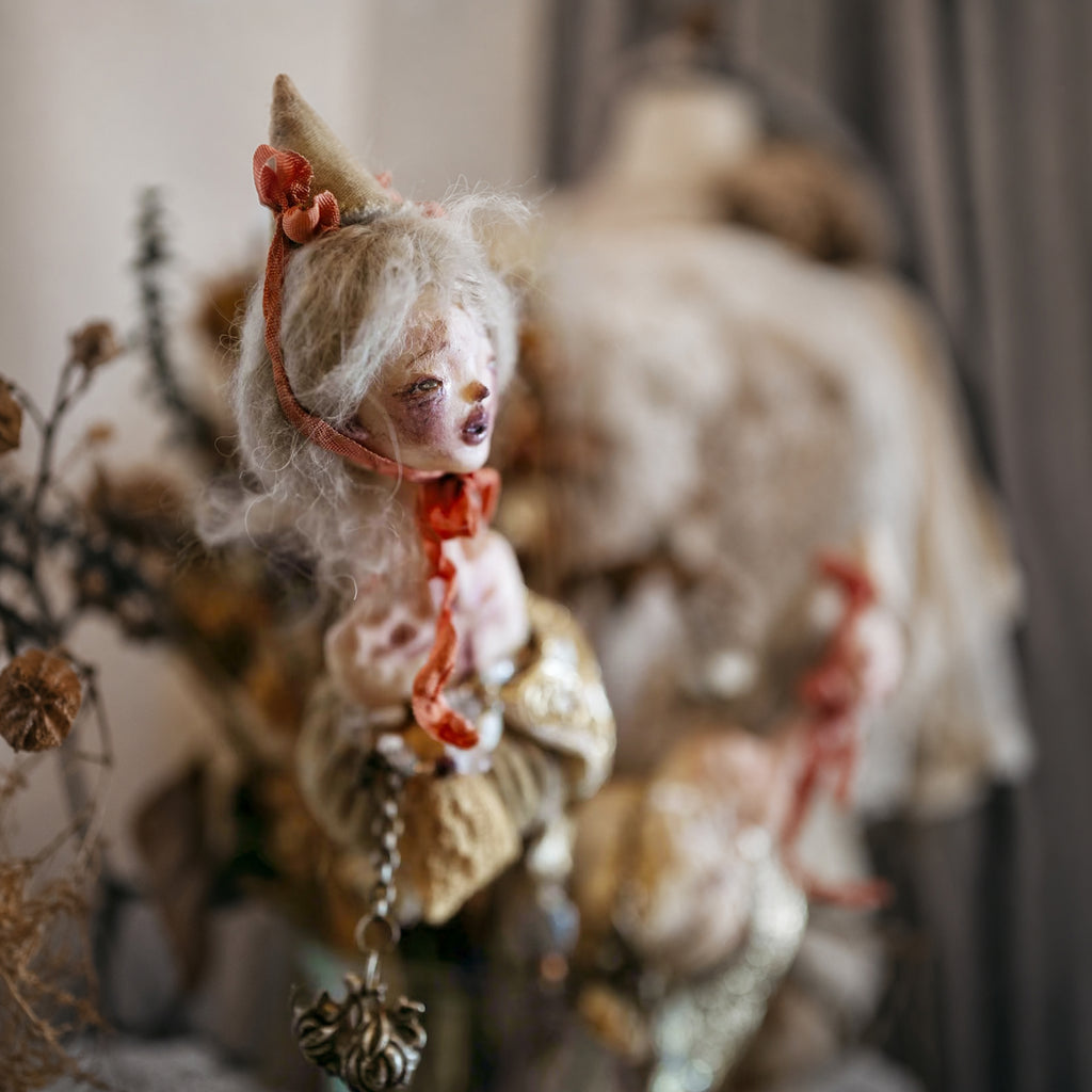 Side view of the Lambwick hand-bell doll's pale hair, cone hat and red ribbon.