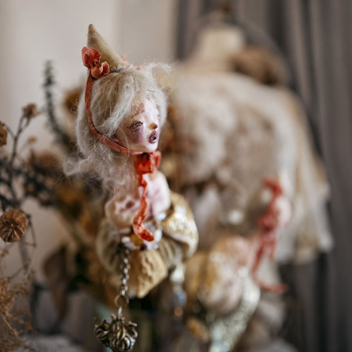 Side view of the Lambwick hand-bell doll's pale hair, cone hat and red ribbon.