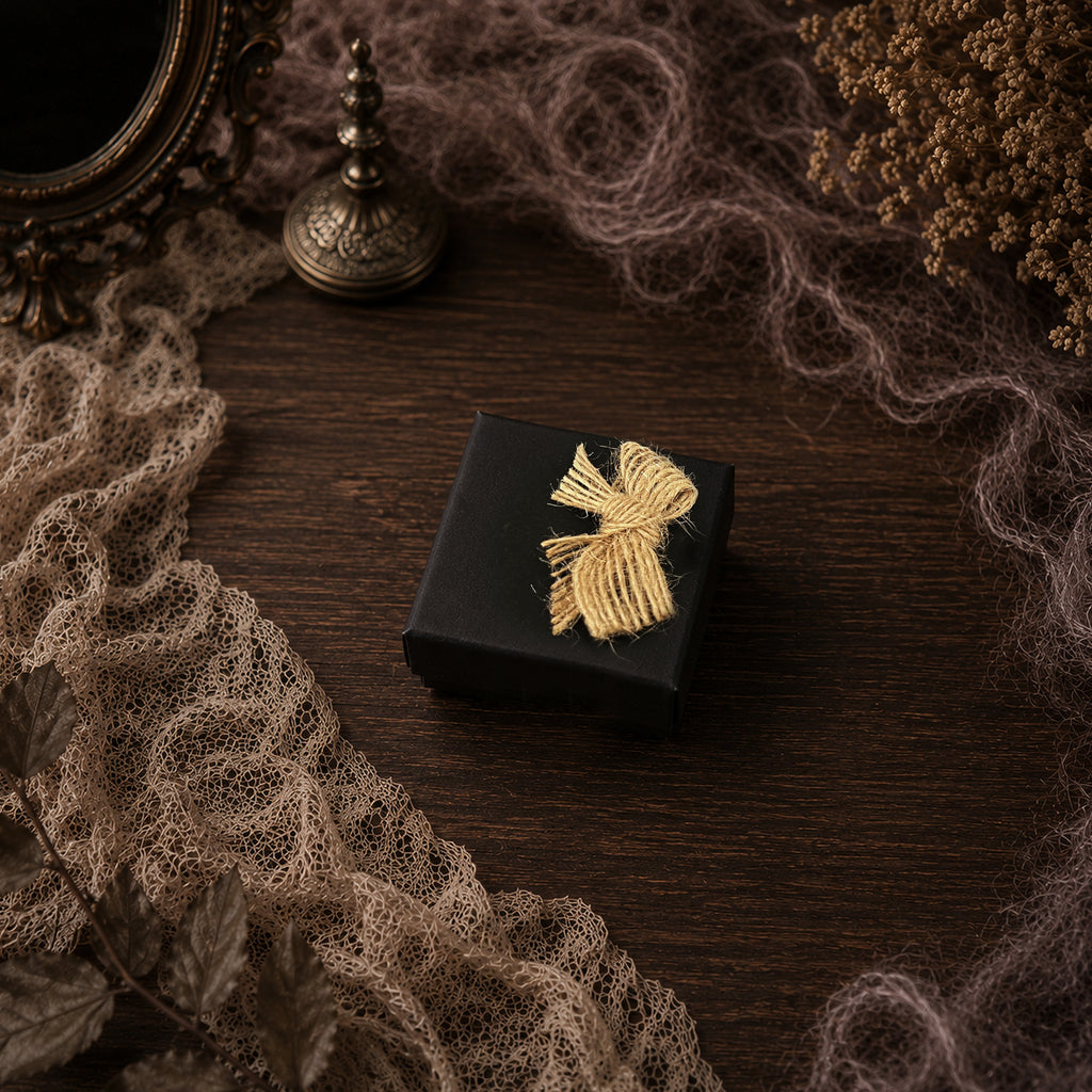 Black Lambwick gift box tied with pale cord, shown on brown lace.