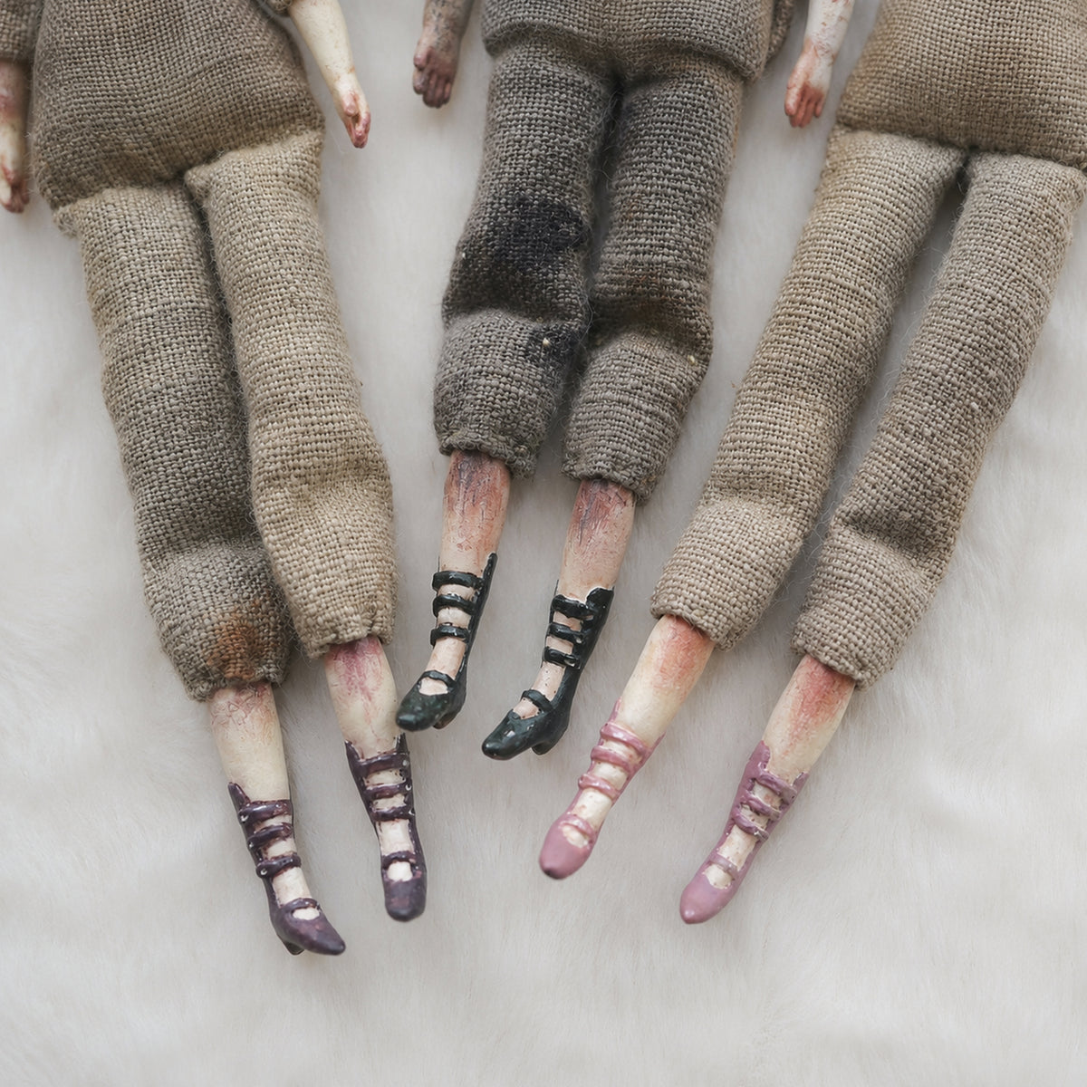 Close-up of Lambwick art-doll legs showing fabric trousers and hand-painted striped stockings.