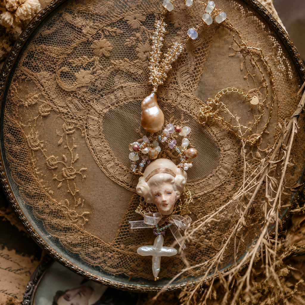 Odette Cross doll necklace arranged in a circle on brown lace.