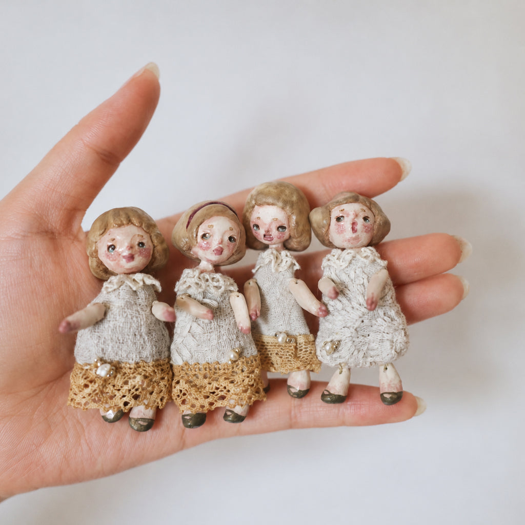 Four miniature Lambwick resident dolls resting together across a hand to show their scale.