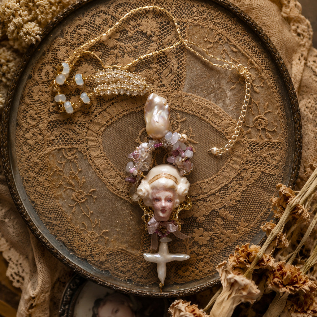 Odette Cross doll necklace with a sculpted face, pale pearl-like beads, faceted beads and a cross drop.