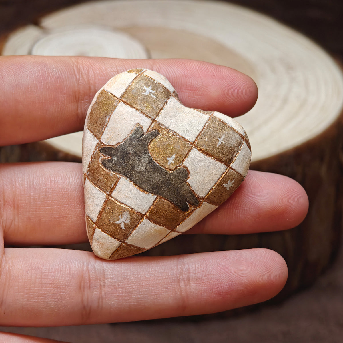 Heart-shaped Winterwood brooch with a resting rabbit on a cream-and-brown checked background.
