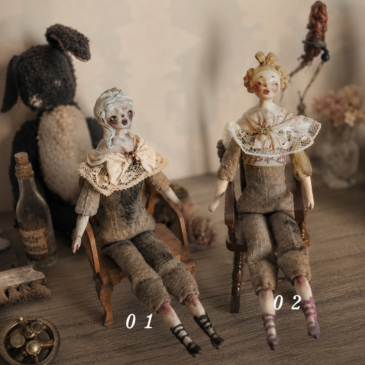 Two seated Lambwick art dolls with pale lace collars and wooden chairs, labeled 01 and 02.