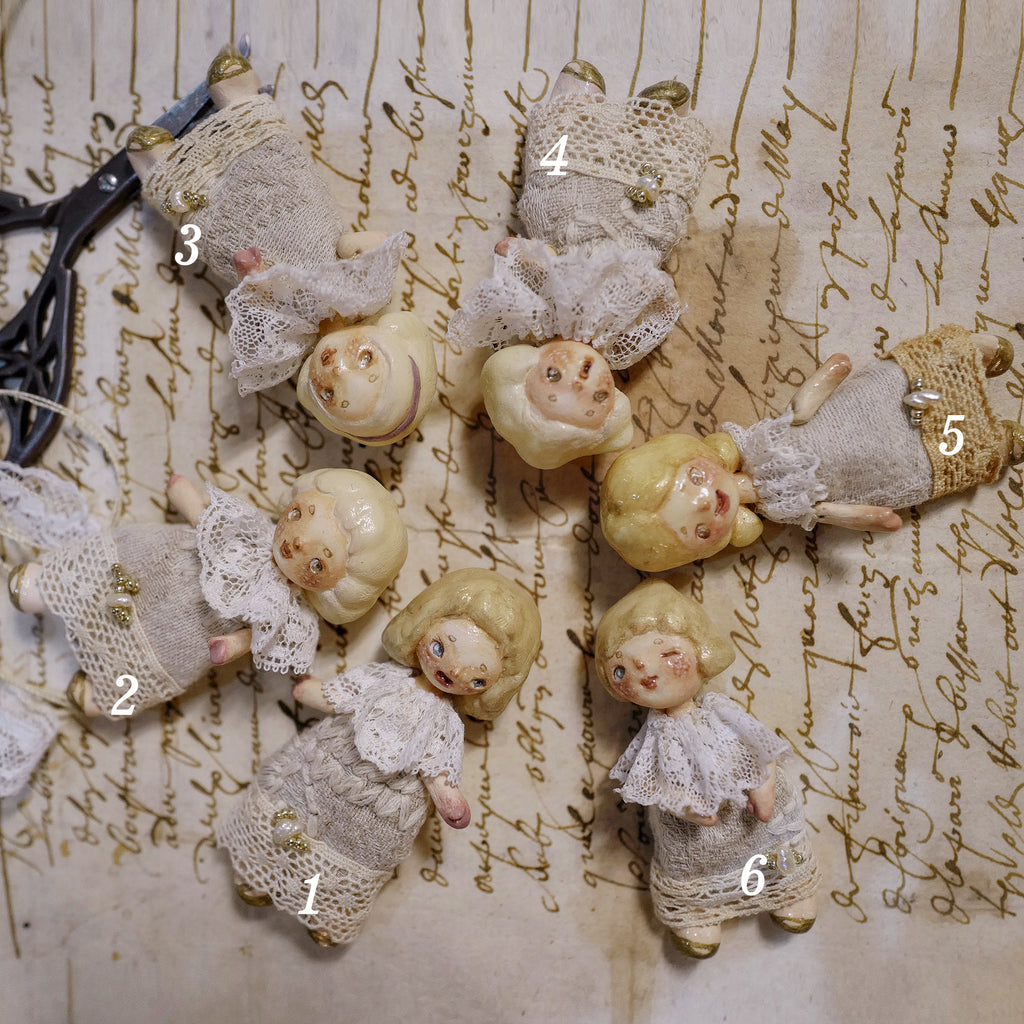 Numbered comparison of six miniature Lambwick resident doll styles arranged on handwritten paper.