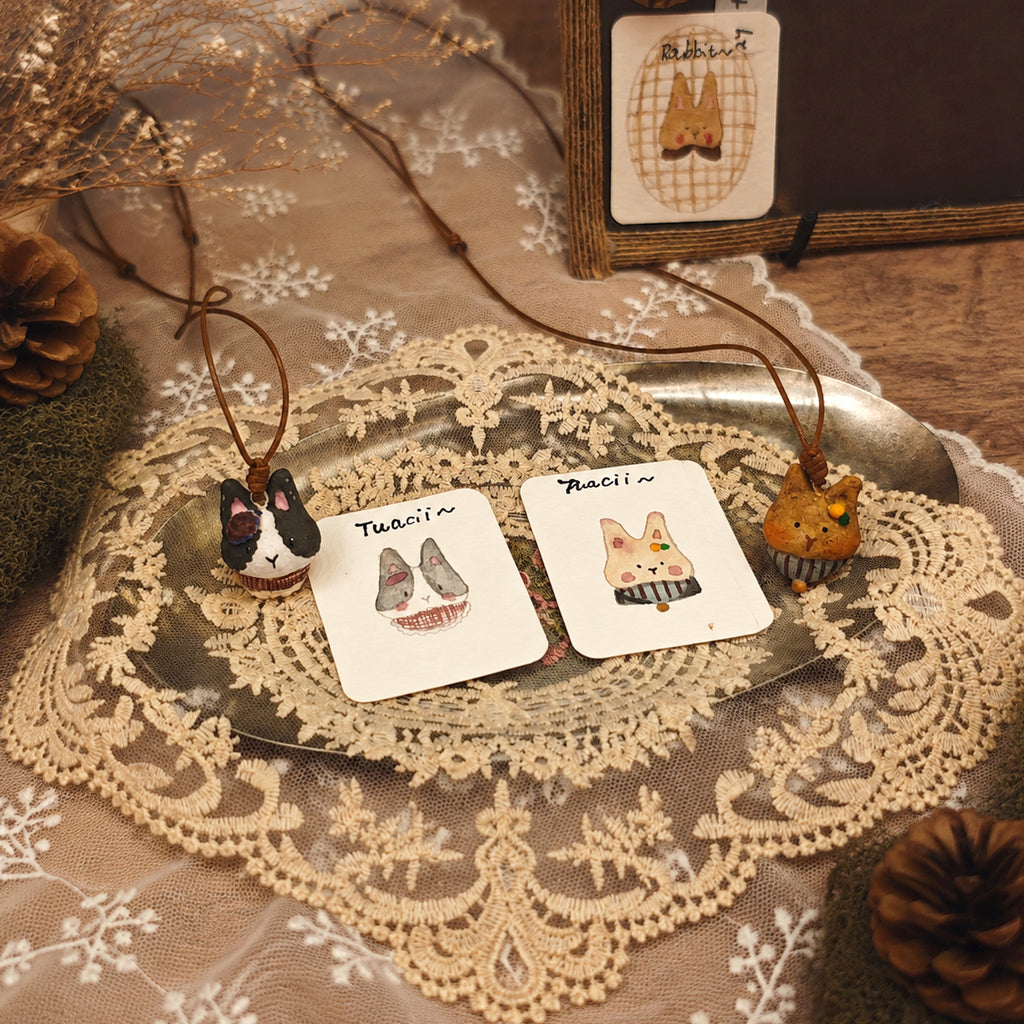 Two Winterwood rabbit pendant necklaces displayed with their illustrated character cards.