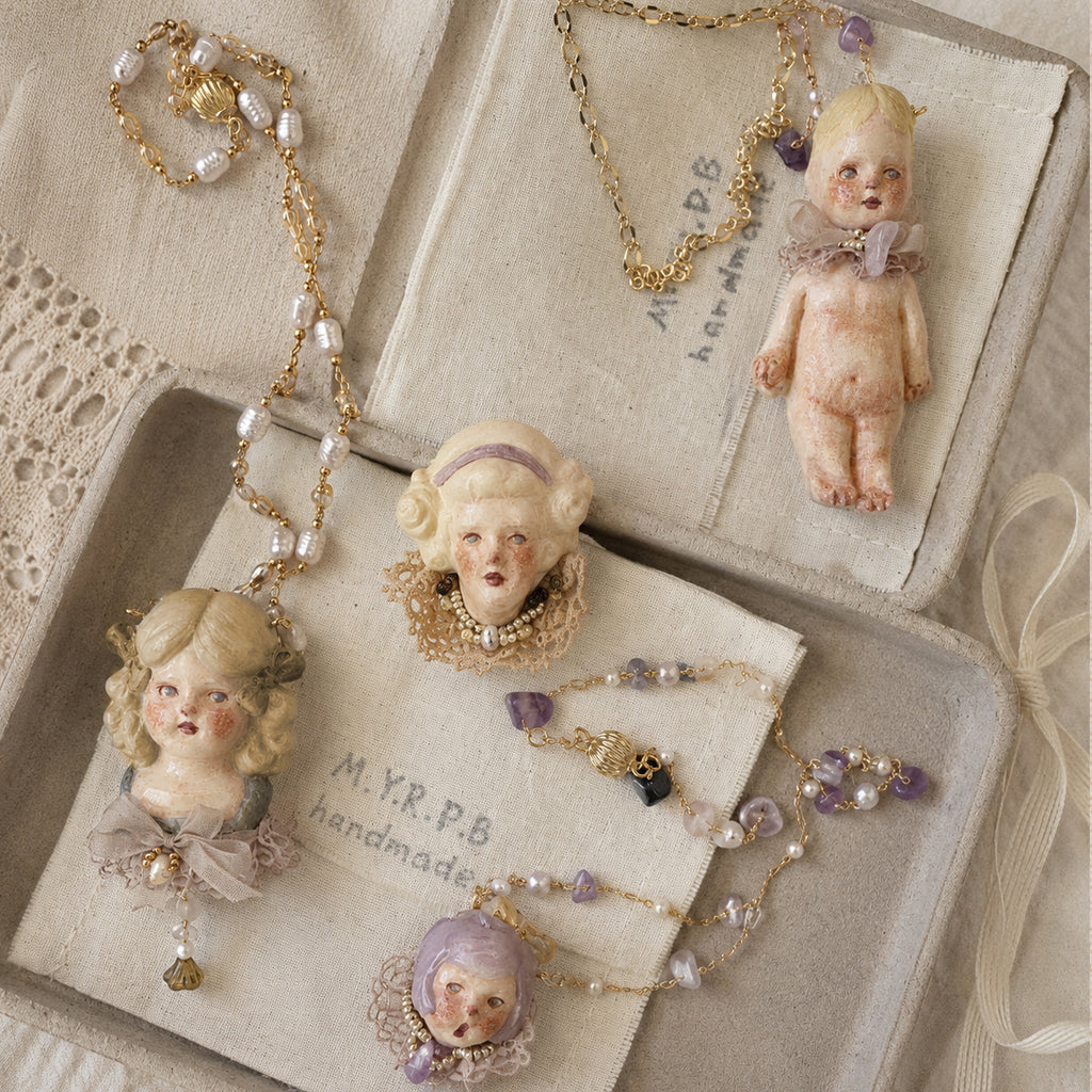 Lambwick doll necklaces displayed inside an open presentation box.