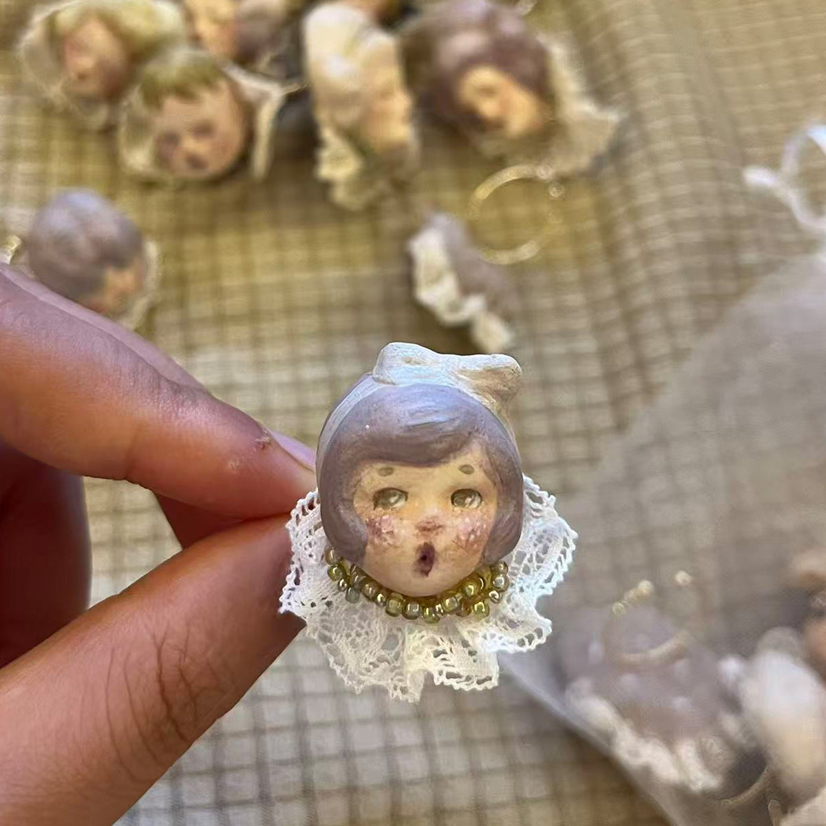 Lambwick doll ring with a lavender bonnet and cream lace collar, shown outdoors.