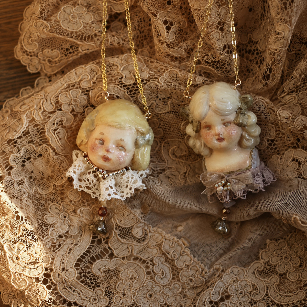 Two blonde Lambwick doll-head necklaces with different lace collars and drop ornaments.