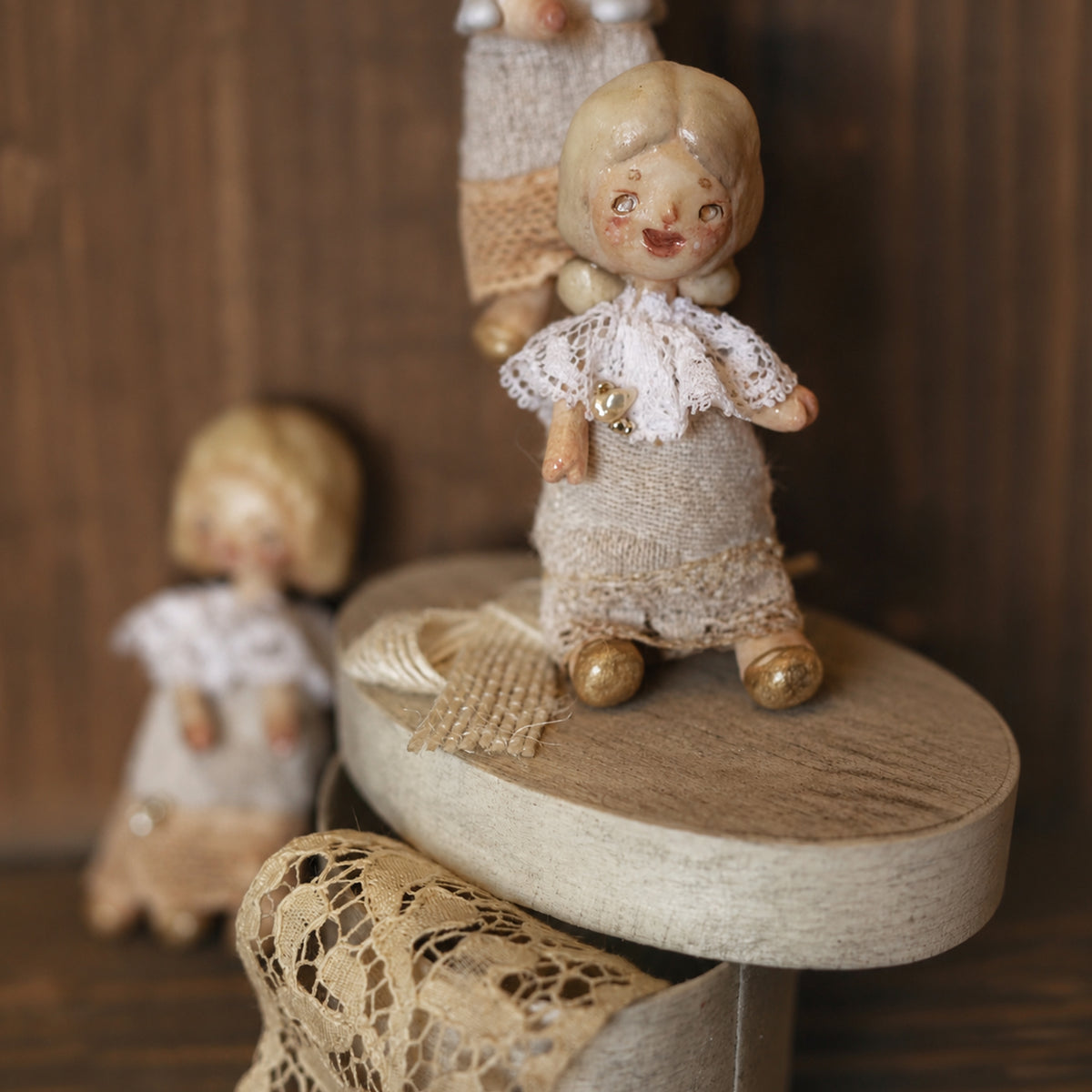 Miniature Lambwick resident doll seated on a round presentation box.