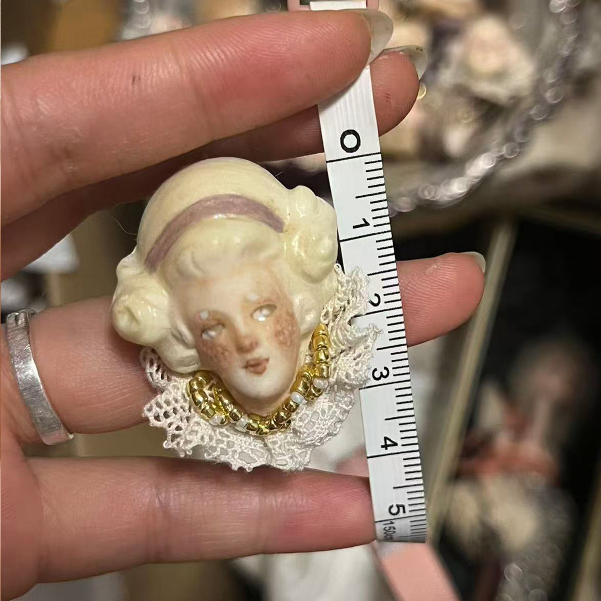 Lambwick mother doll ring with blonde waves and a mauve headband beside a measuring tape.