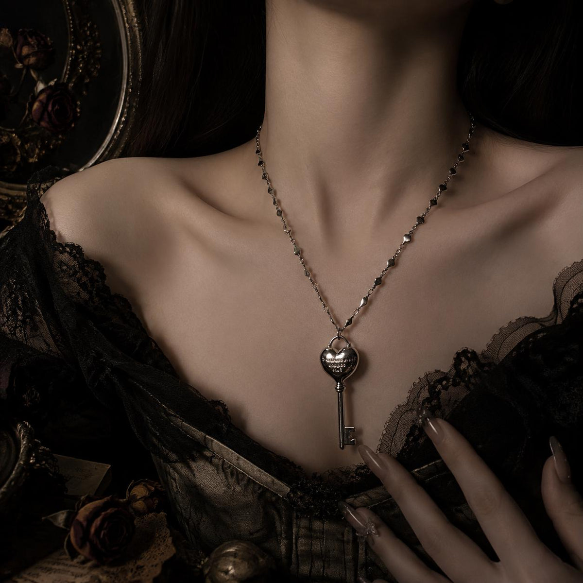 Heart-key necklace worn alone over a black lace neckline.