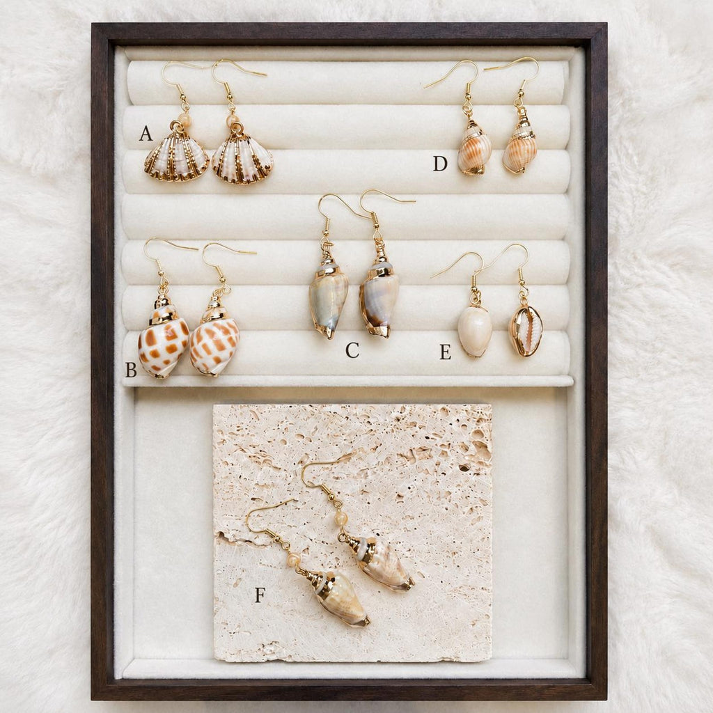 Comparison display of natural shell-earring styles labeled A to F in a jewelry tray.