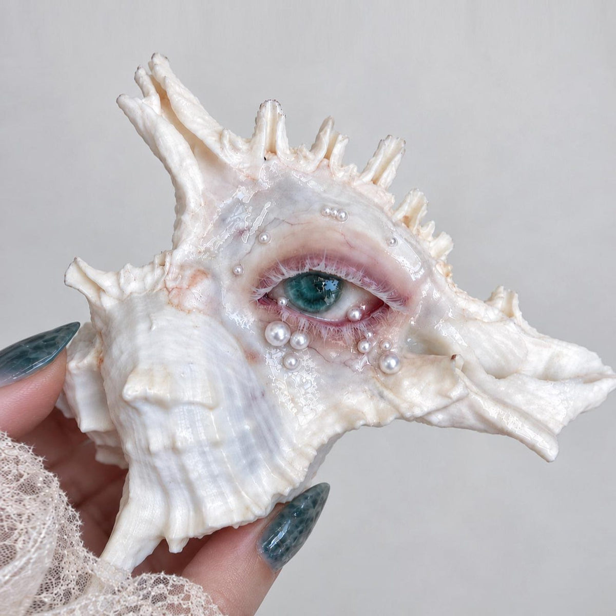 Verdant Gaze green-eye spiked shell candle holder held in a hand.