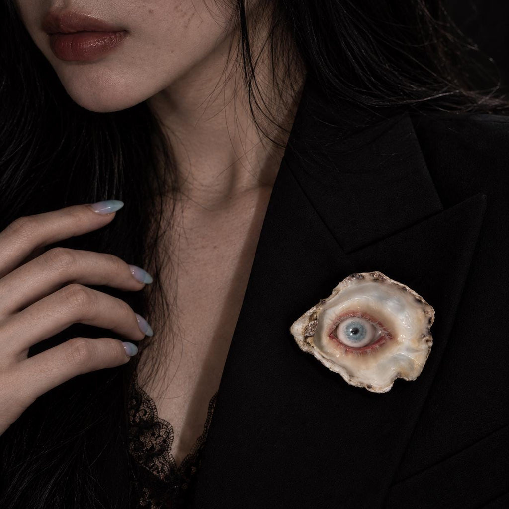 Wander Eye shell-eye brooch worn on a black blazer.