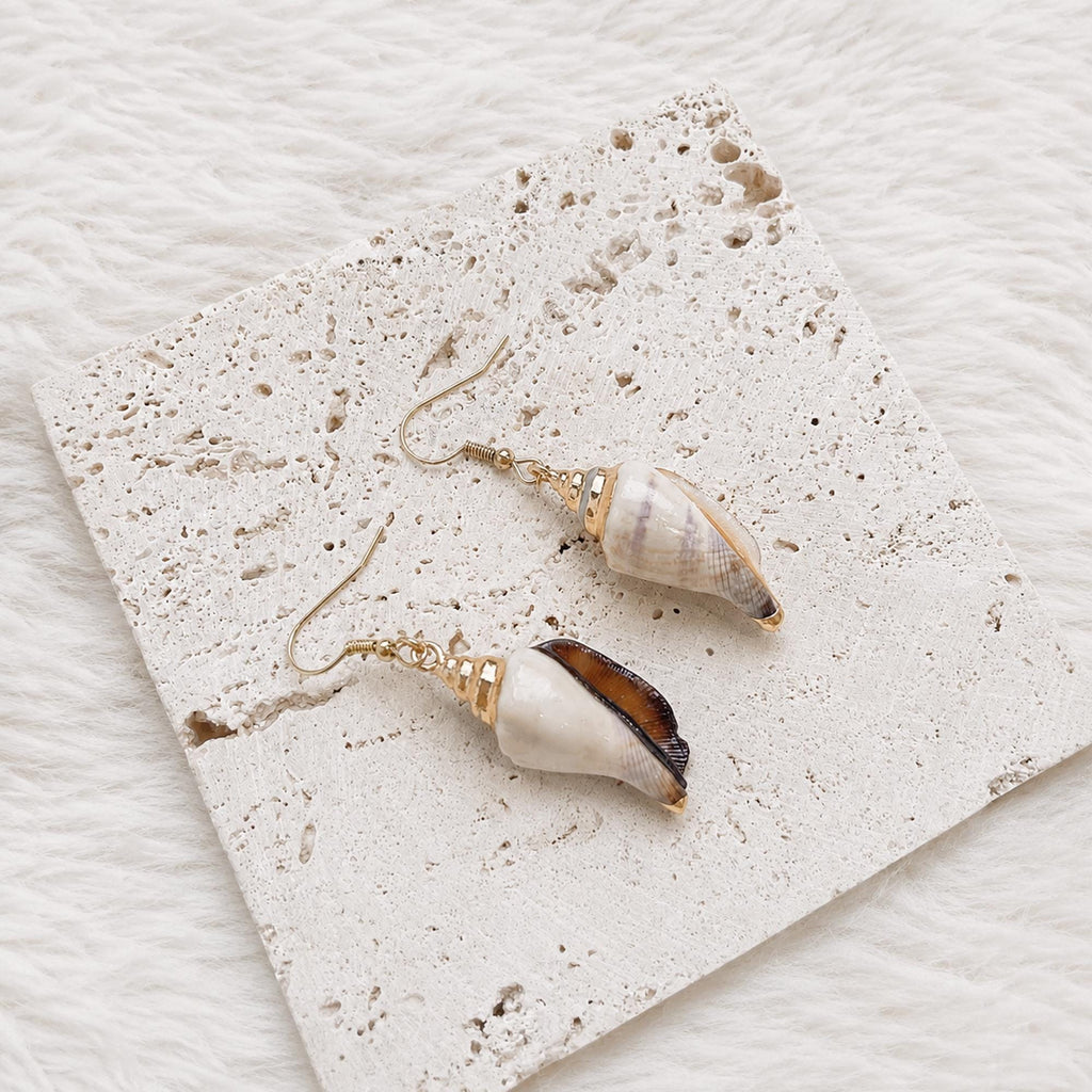 Angled view of pointed shell earrings with pale reflective surfaces.
