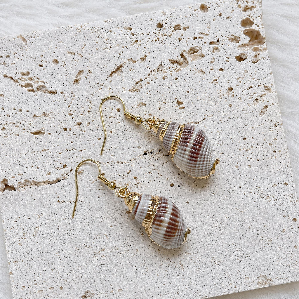 Angled view of striped conch-shell earrings with gold-tone fittings.