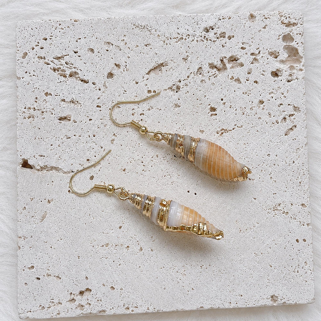 Front-and-back view of elongated spiral shell earrings with pale interiors.