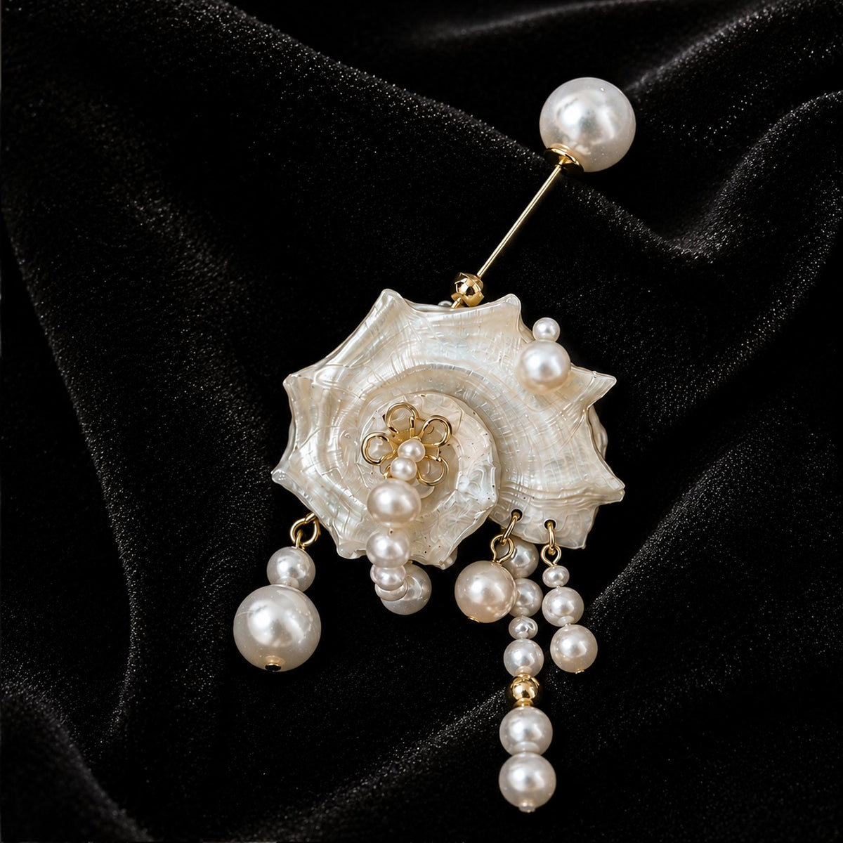 Conch-shell brooch with hanging pale beads and a pearl-topped pin on black velvet.