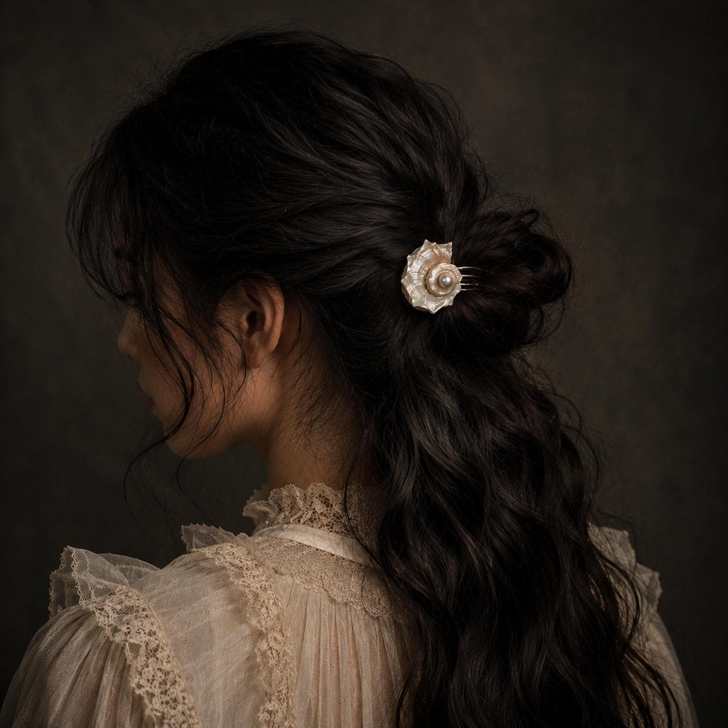 Conch-shell hair comb worn above a loose bun.