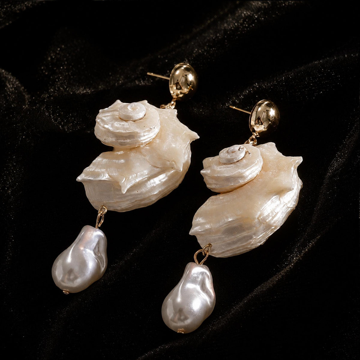 Angled view of spiral conch-shell earrings with pale teardrop beads.