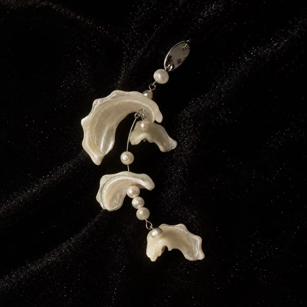 Single shell-fragment drop earring with three pale wavy sections and small beads.