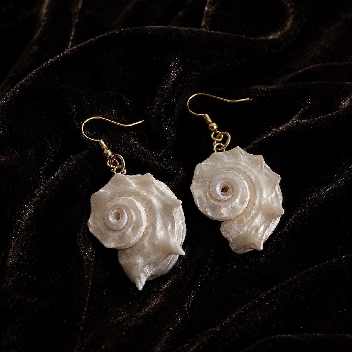 Angled close view of two iridescent conch-shell earrings.