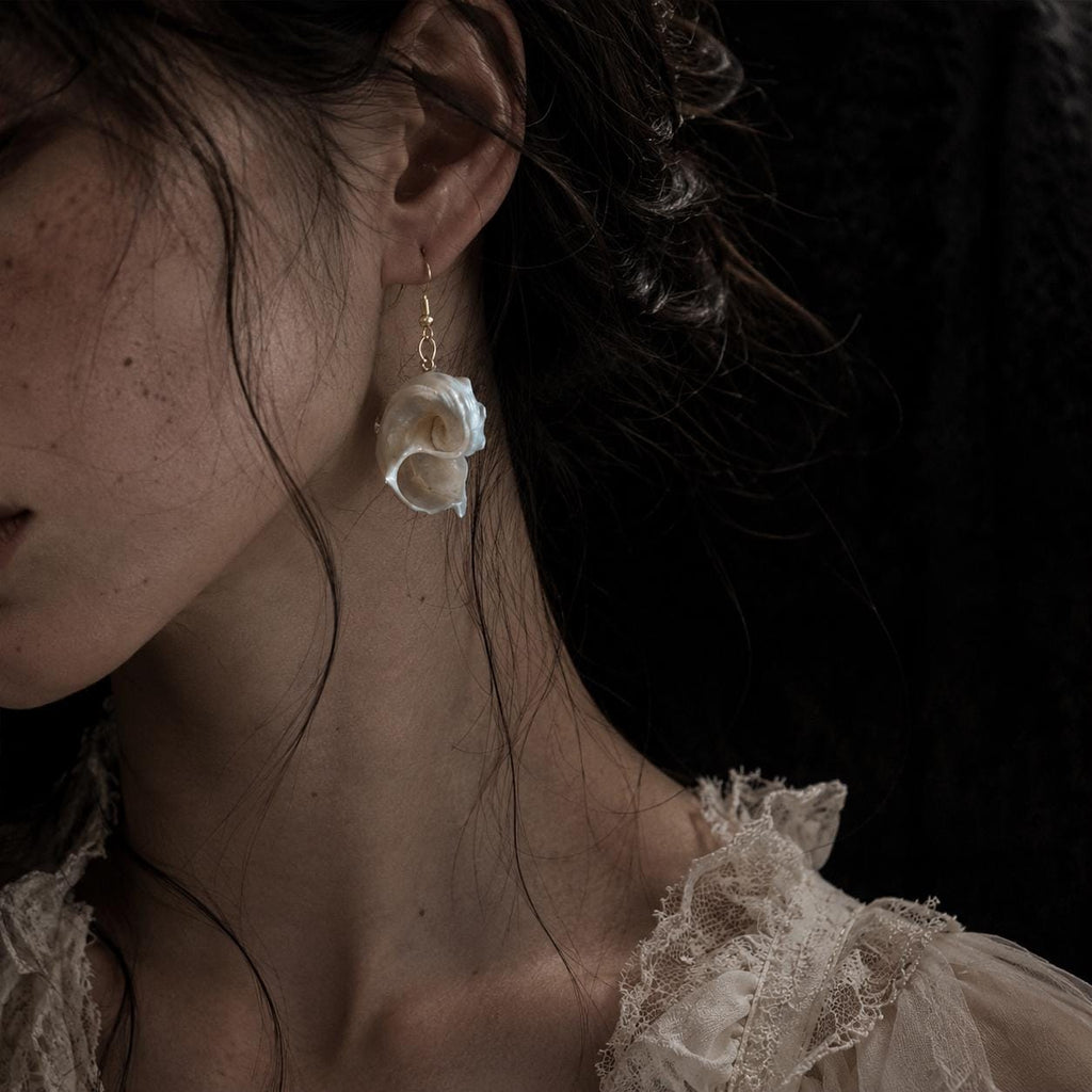 Side and reverse view of a spiral conch-shell earring worn on an ear.