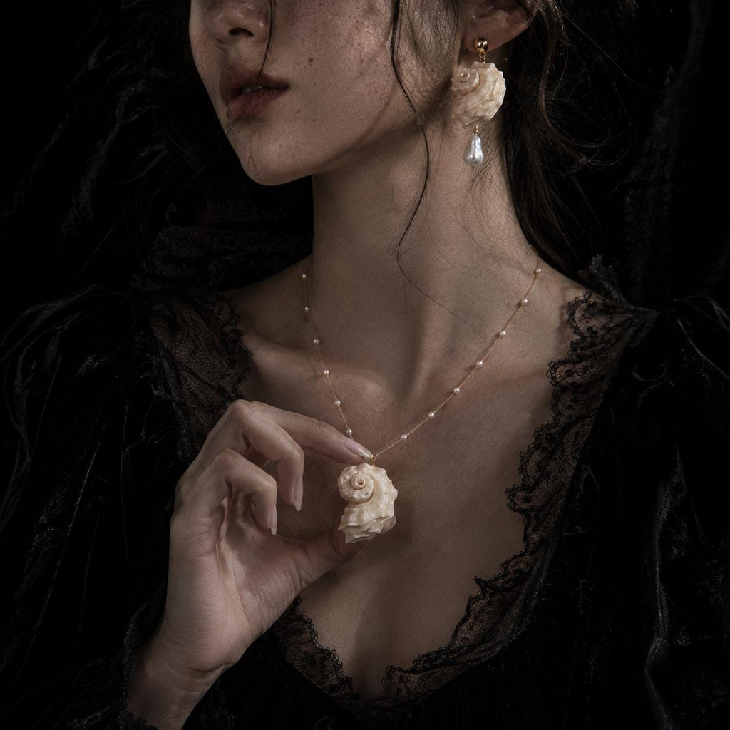 Matching spiral conch-shell necklace and earrings shown with a dark lace outfit.