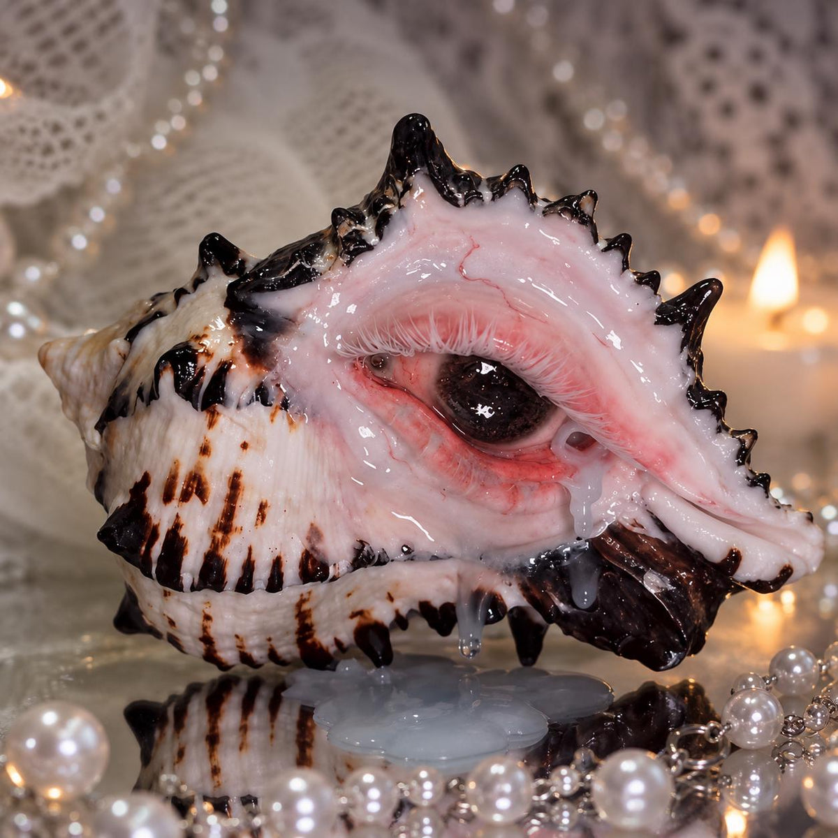 Close view of the Mourning Tide pink eye and spiked shell beside candlelight.