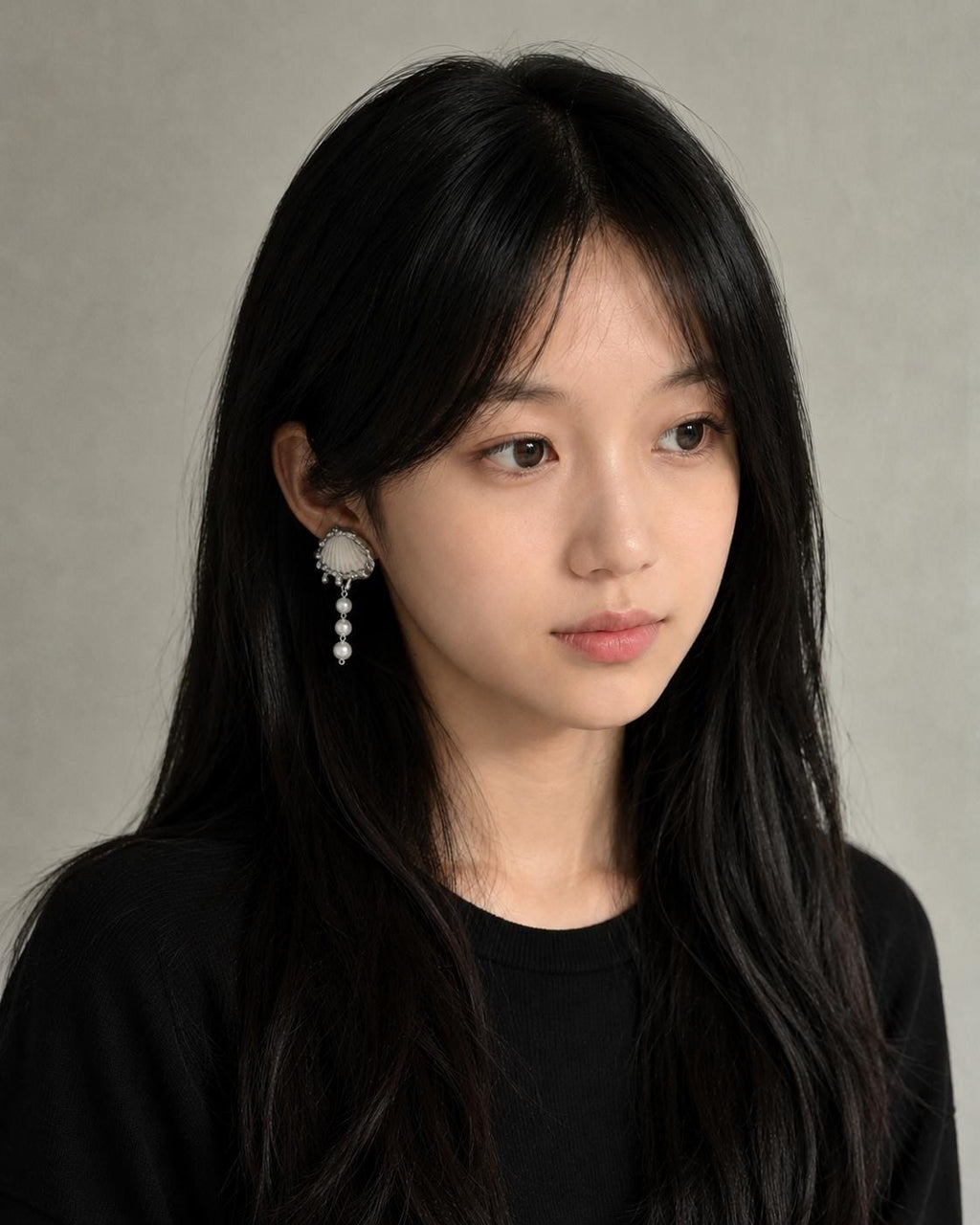 Shell Pearl Drop worn as an earring beside dark hair.