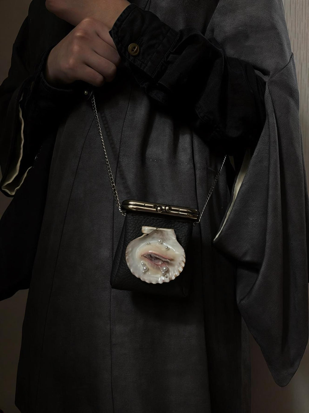 Oyster Eye Mini Crossbody Bag worn on a long chain across a dark outfit.