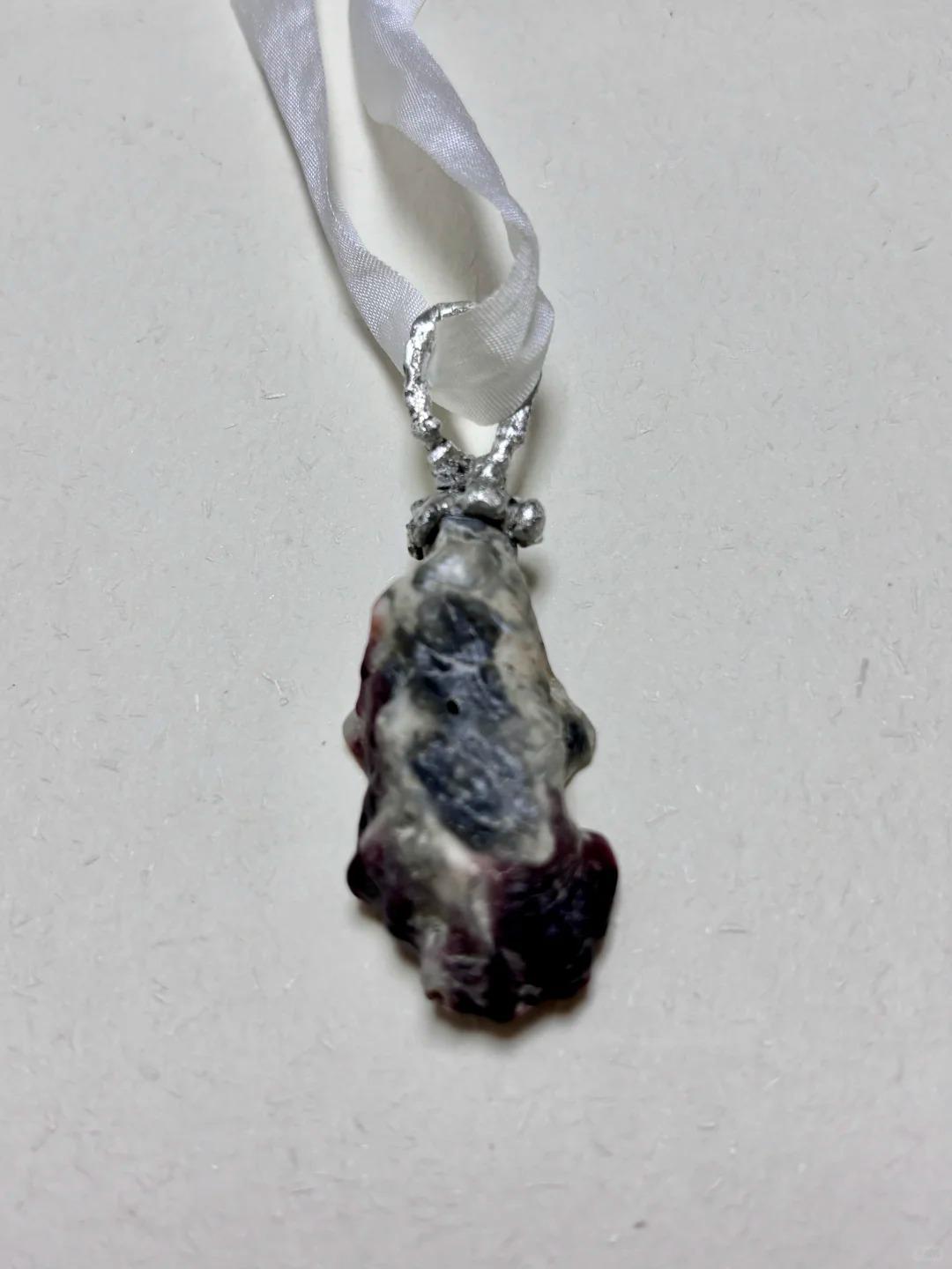 Shell Pearl Talisman pendant hanging vertically from ivory ribbon.