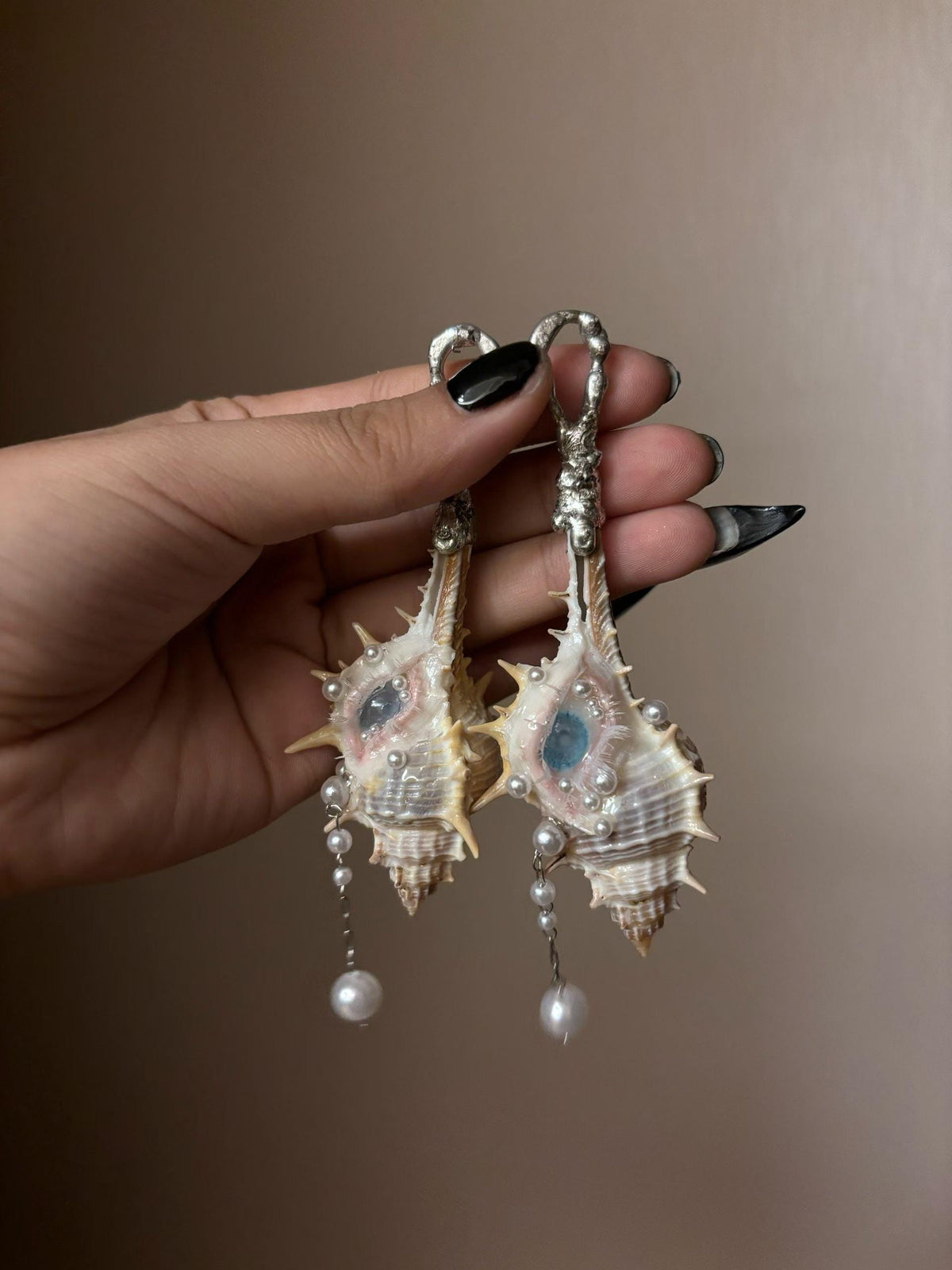 Two Conch Eye Talisman pieces with large metal pin attachments, held together.