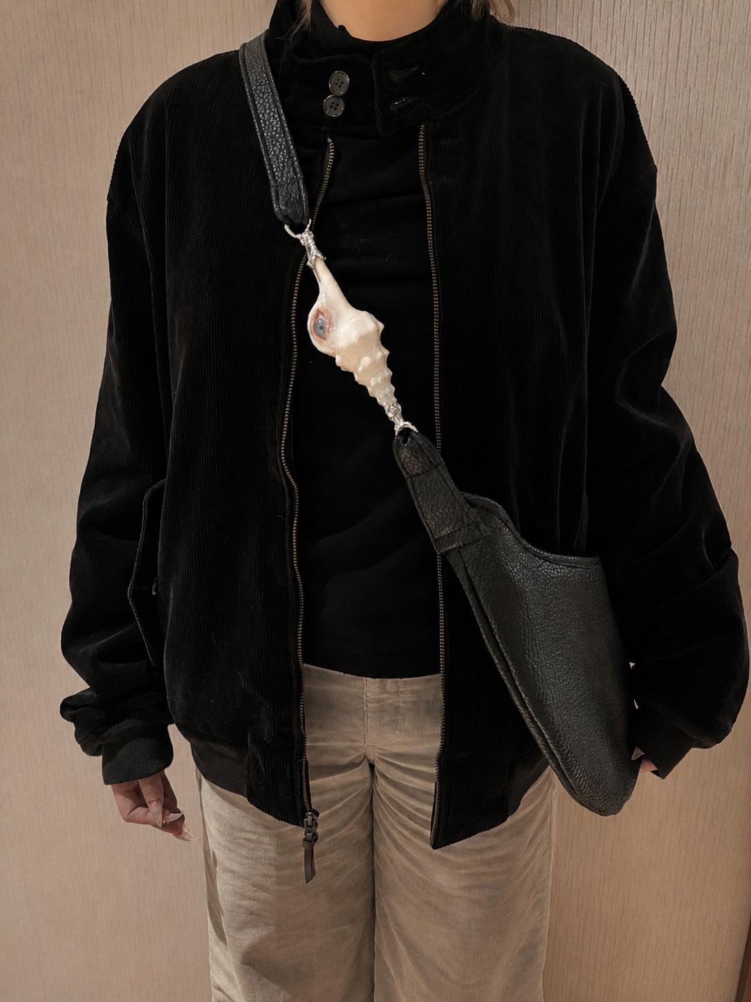 Long Conch Eye Shoulder Bag worn across a black top, with the shell-eye ornament at the chest.