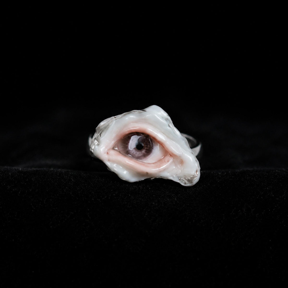 Brown-pupil oyster-eye ring shown from the front on black velvet.