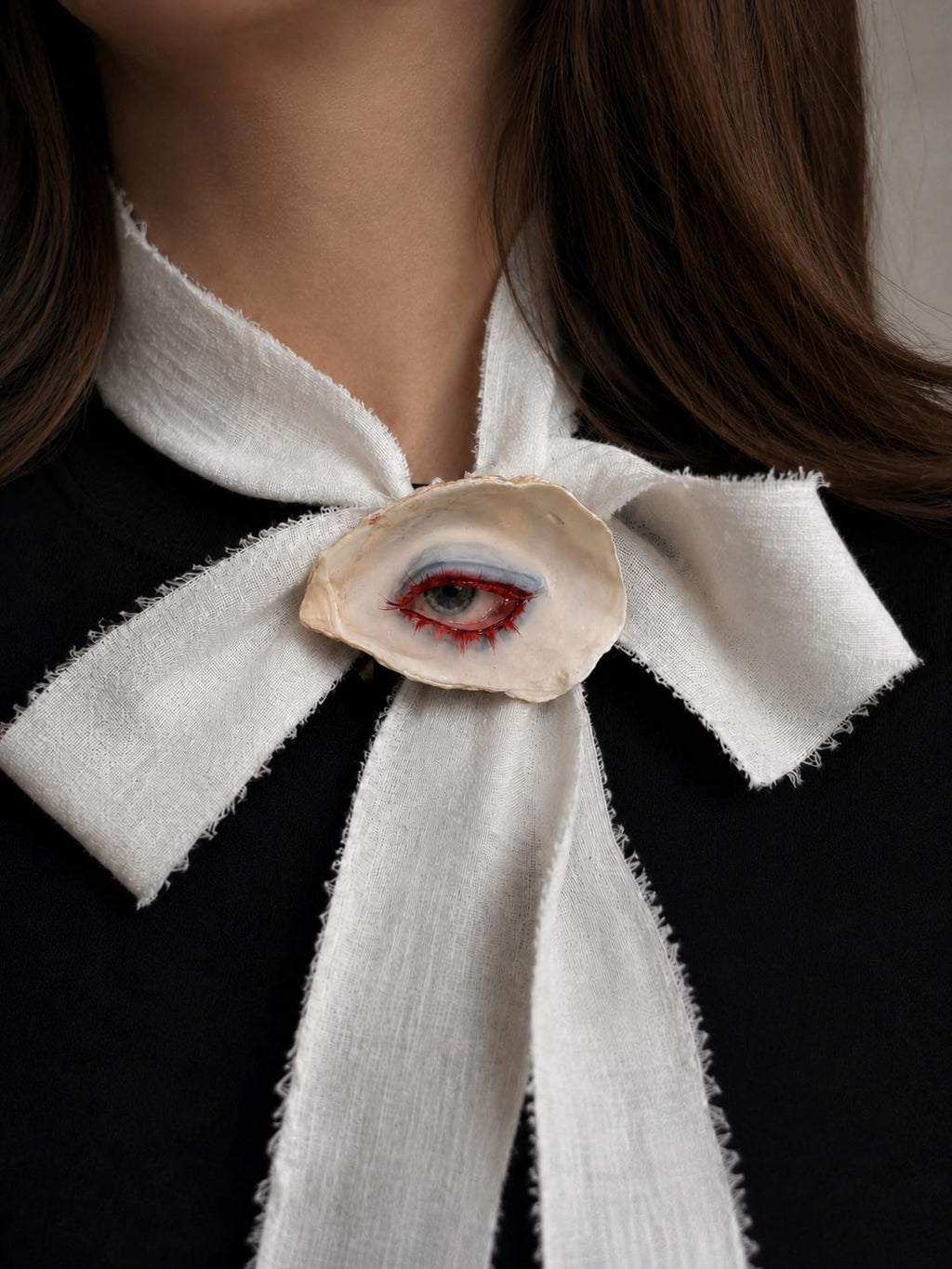 Red-Lash Oyster Eye worn at the center of a large ivory ribbon bow.